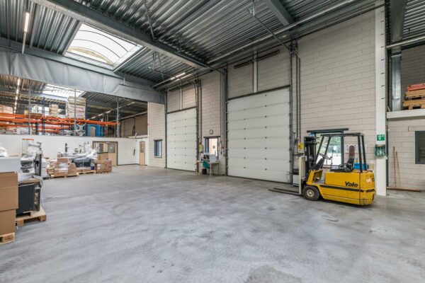 Binnenzicht van een ruime, moderne bedrijfshal aan de Laan Blussé van Oud-Alblas met een gele Yale-heftruck en opslagrekken op de achtergrond.